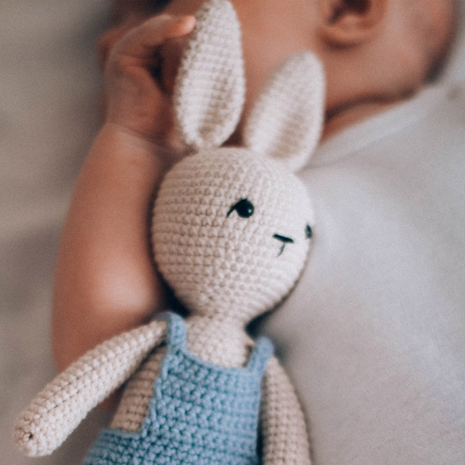 Baby beruhigen: Baby liegt mit Stofftier im Bett