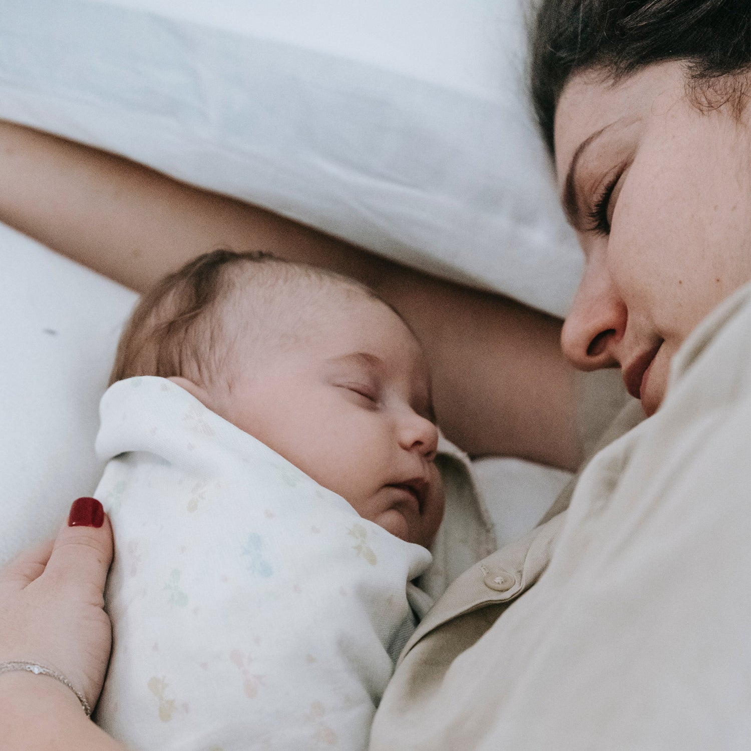 Mutter liegt mit ihrem Baby Seite an Seite im Bett